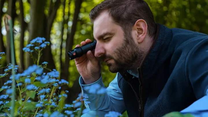 a man looking at a flower through the monovid from nearby
