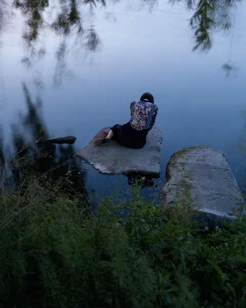 Woman sitting on a stone by the lake
