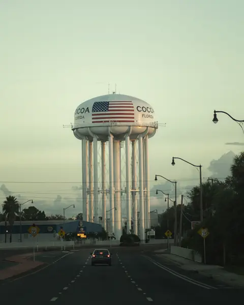 An empty road leads to a water tower labelled ‘Cocoa, Florida’.