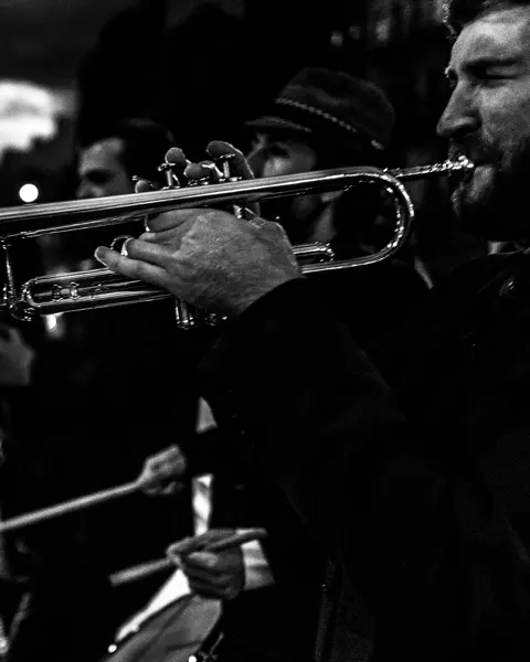Several musicians and a trumpeter in the foreground play music in the street