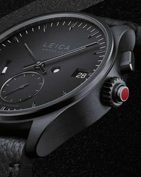 Close-up of a black Leica watch on a black background.