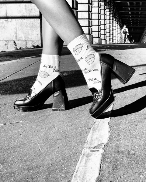 Close-up of legs in high heels on a street under a bridge in black and white.