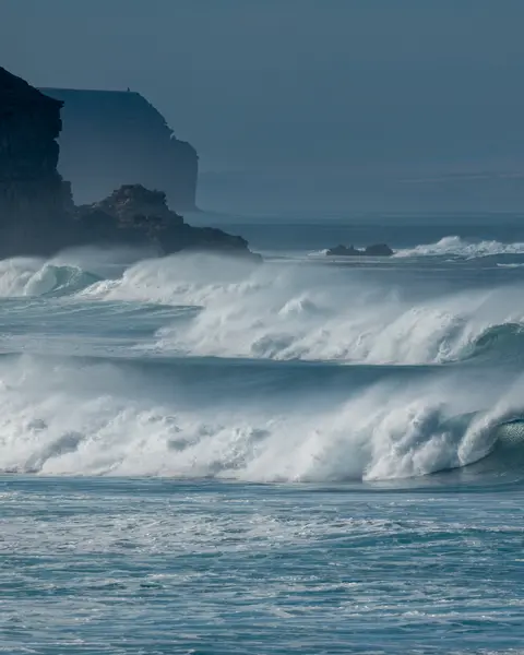 Waves breaking on a coastline under a blue sky