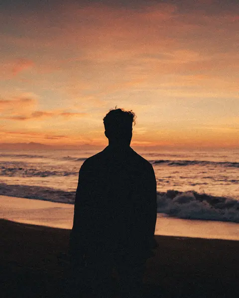 Silhouette of a man watching the sunset on the beach.