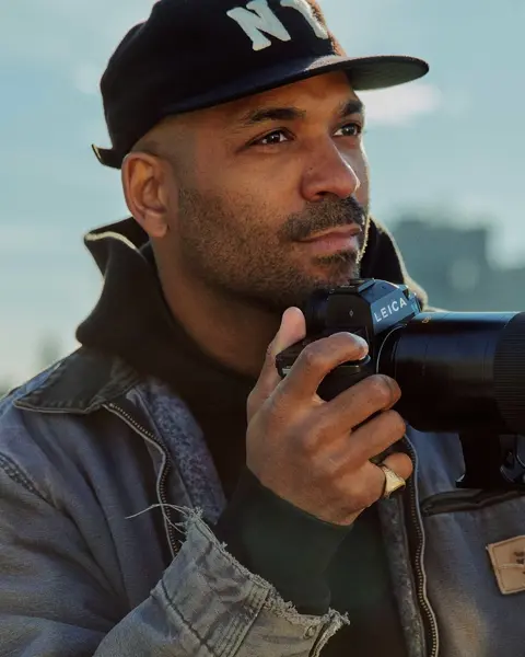 A young man is taking pictures with a cityscape in the background