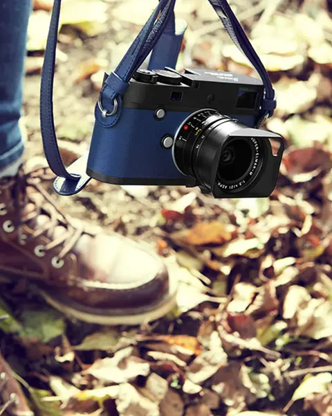 Man in the fall leaves with blue leica camera