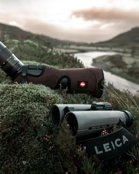 Leica-binoculars-Noctivid-8x42-and-spotting-scope-lying-in-a-meadow-in-the-Scottish-Highlands