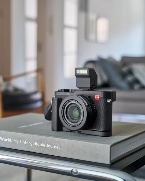 Leica D-Lux 8 placed on a book lying on a table.