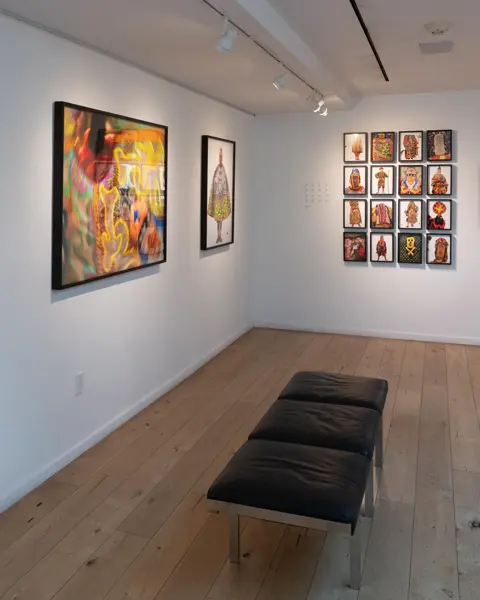 Gallery with colourful portraits of people in traditional dress from different cultures, wooden floor and modern bench seat.