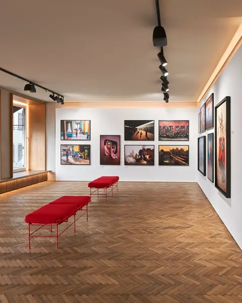 Exhibition space with red benches and photographs of people and places from all over the world.
