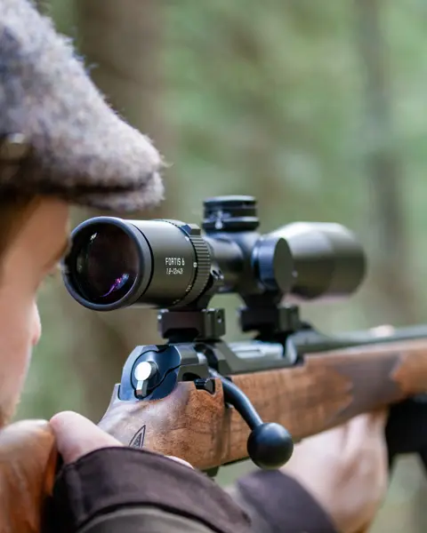 The focus is on the Leica Fortis while a hunter gazes intently through the scope
