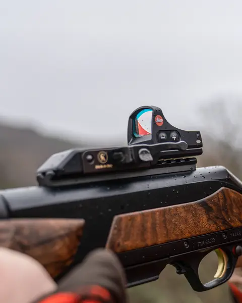 The focus in this image is on the Leica Tempus, where a man is looking intently through the red dot sight