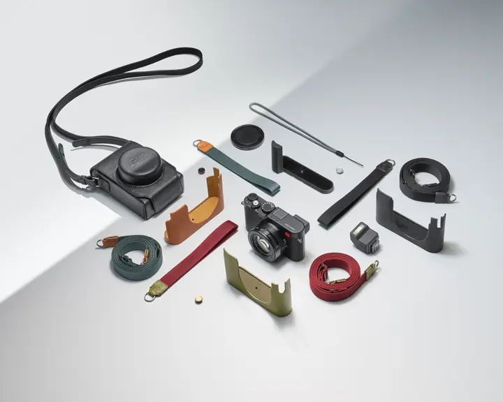 Camera with various accessories, such as straps and protective covers, on a light background