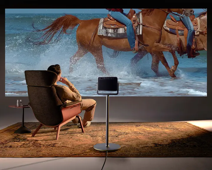 A man is sitting in front of a screen watching a Leica Cine Play 1 projection.