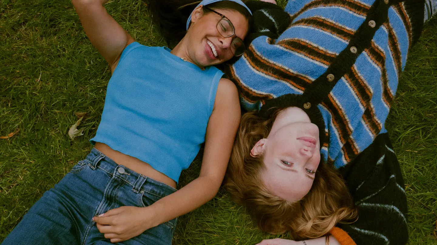 2 girlfriends lying on a green meadow