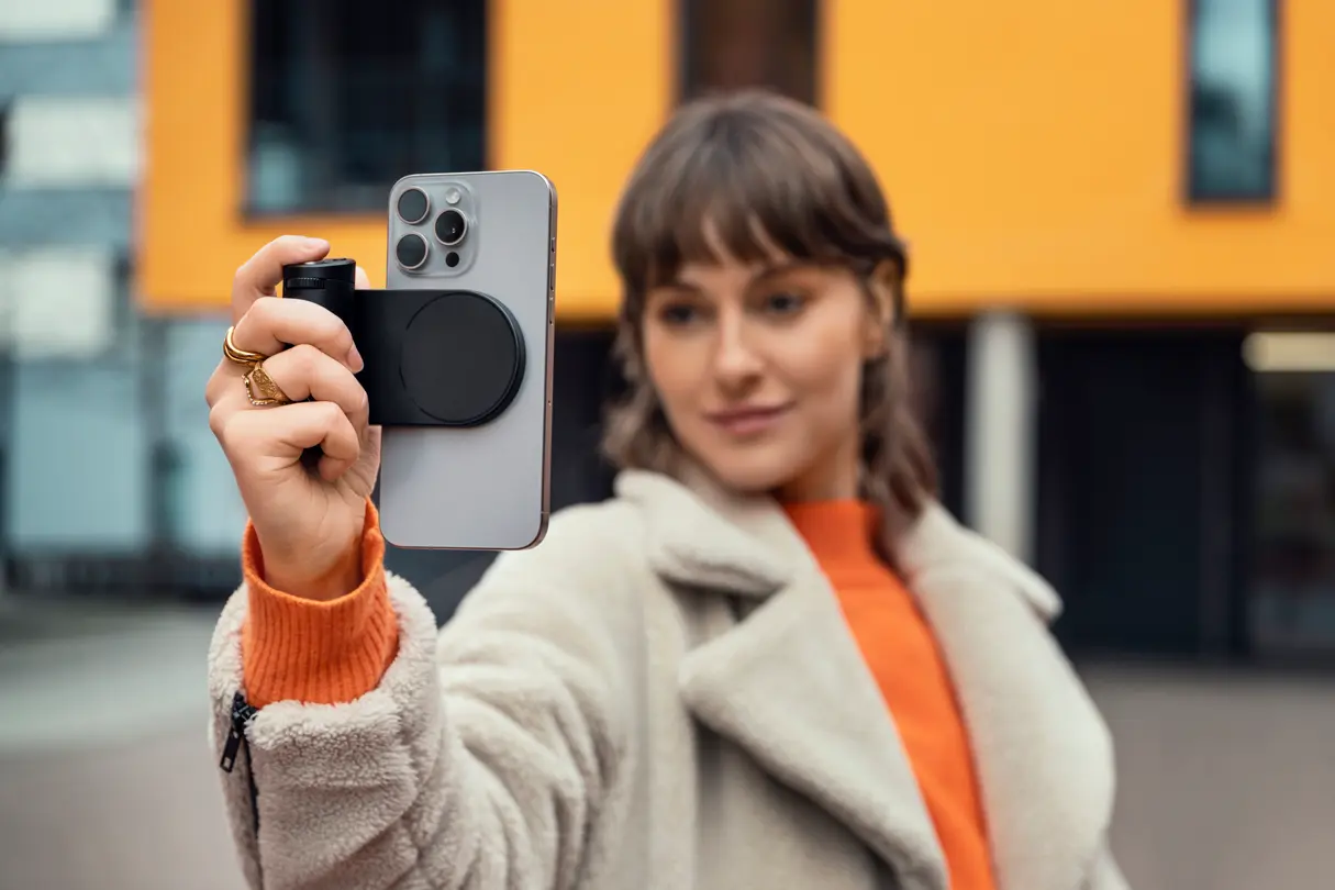 Woman taking a picture in portrait format with the Leica LUX grip