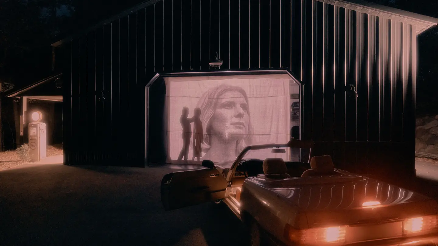 A car shines its light onto a screen.