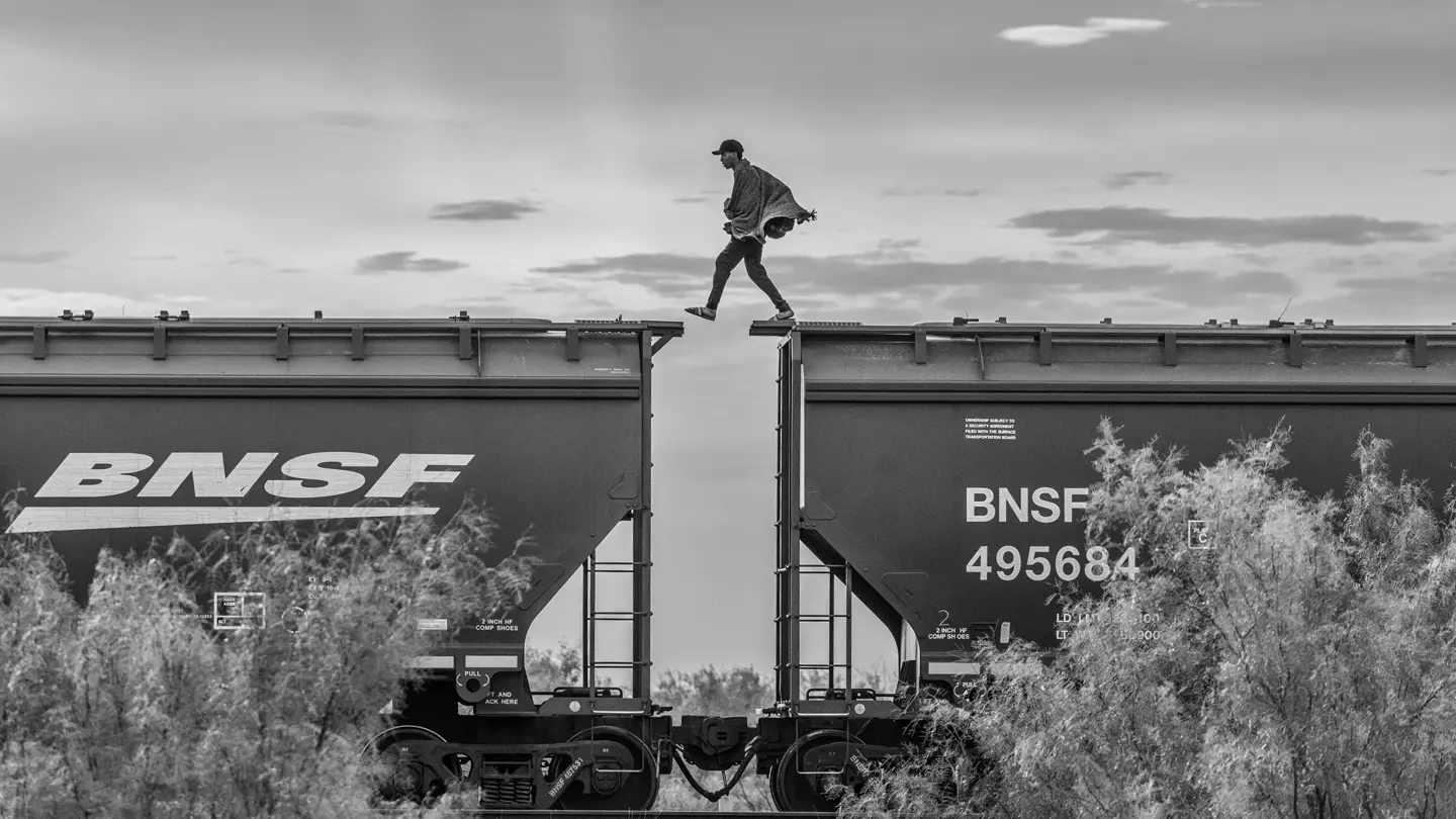 A person is jumping from train car to train car.