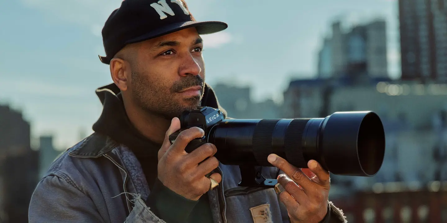 A young man is taking pictures with a cityscape in the background
