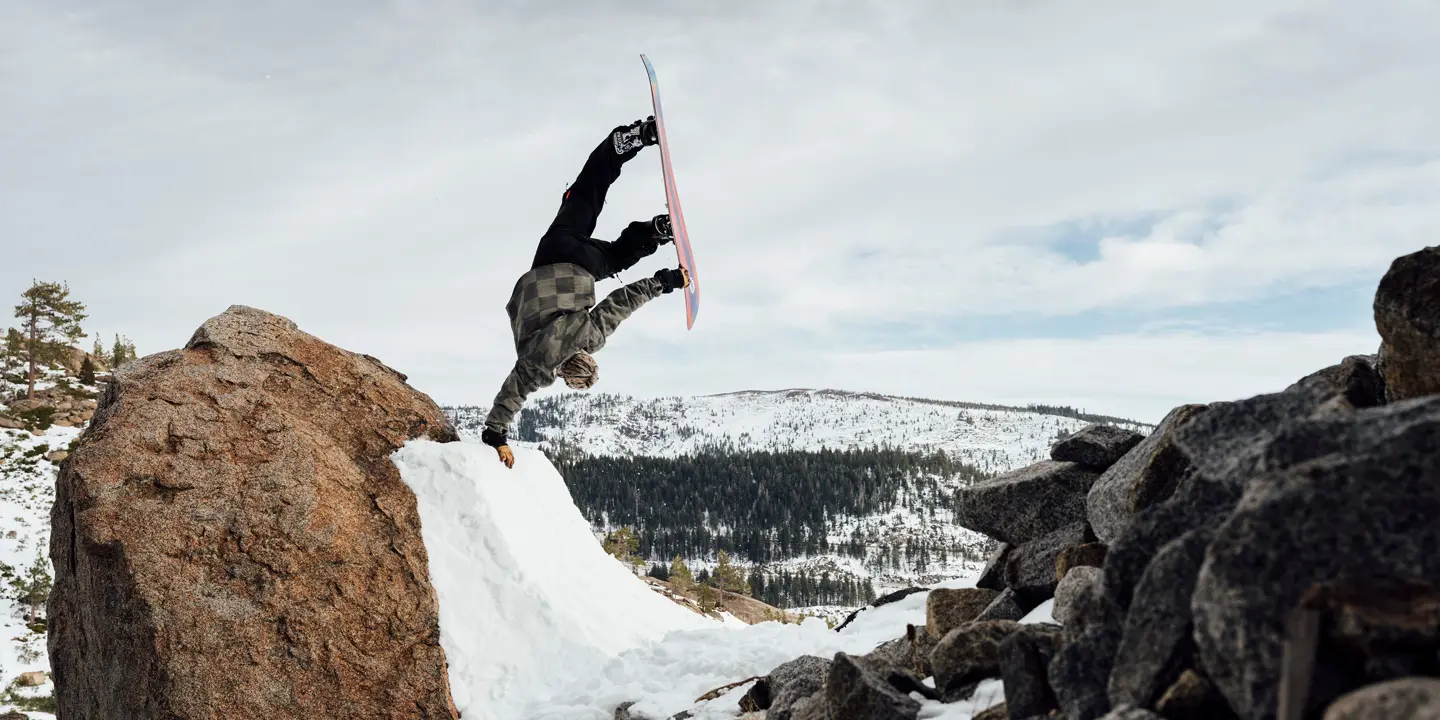 Snowboarder does a one-armed handstand on a ramp in the mountains