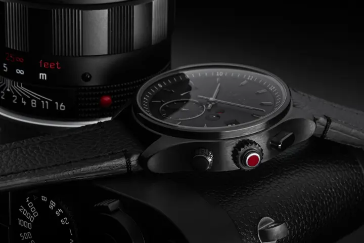 Black leica watch with leica camera behind the watch