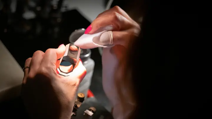 Hands-cleaning-an-optical-component-in-the-Leica-binocular-manufacturing