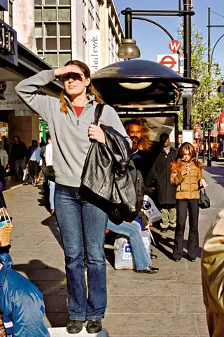 A woman who was standing on a bench, appearing to be looking for something and other people
